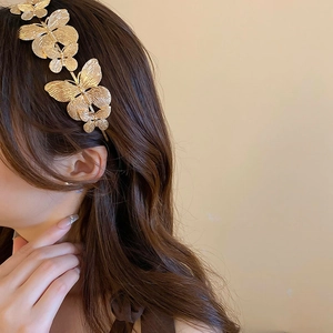Detail of golden metal butterfly headband with realistic wing textures on brown hair