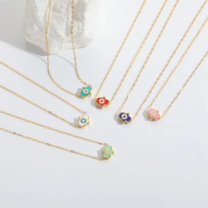 Multiple gold Hamsa hand necklaces with colorful enamel eye pendants on a white surface