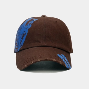 Close-up of brown cotton baseball cap with blue graffiti print and distressed brim edges