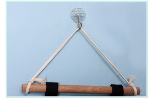 Detail of adhesive wall hook and wooden rod with cotton rope for bedside storage bag