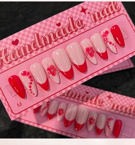 Detail of handmade pink press-on nails with red French tips and floral patterns in size M