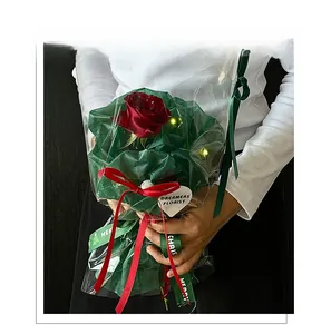 Single red rose bouquet with festive LED lights, green wrapping, and Merry Christmas ribbon
