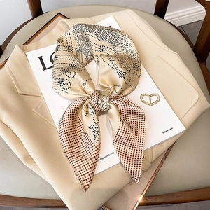 Polka dot silk scarf tied in a bow with a heart brooch on a beige blazer detail