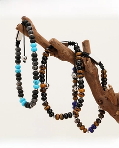 Dettaglio di bracciali in occhio di tigre e lapislazzuli su un ramo di legno naturale
