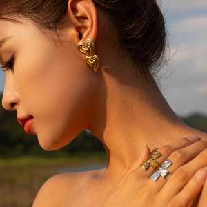 Close-up of a woman wearing 18K gold liquid hammer textured double heart earrings