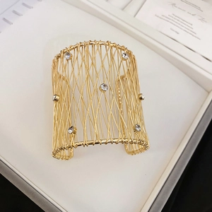 Detalle de brazalete trenzado hueco chapado en oro con brillantes piedras de cristal