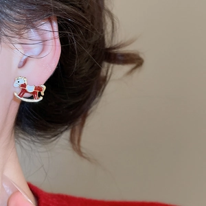 Gros plan d'une boucle d'oreille cheval à bascule rouge et blanc portée par un mannequin