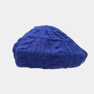 Close-up of dark blue cable knit beret showing textured wool pattern and craftsmanship