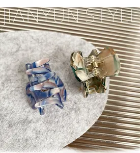 Detail view of mini acetate claw clips with marble texture and golden springs