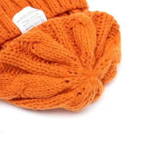 Chic orange chunky knit beanie for women featuring textured cable pattern and a side label