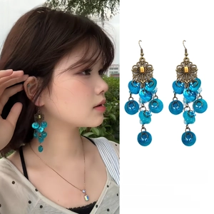 Macro detail of Bohemian flower earrings with blue bead tassels and antique bronze finish