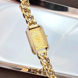 Macro detail of gold rectangular watch dial with rhinestones and chunky metal chain