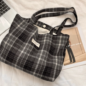 Detail view of checkered tote bag with metal magnetic clasp and woven brand label