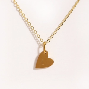 Gros plan du collier coeur doré avec la lettre L gravée sur une chaîne en or