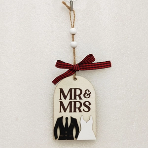 Detail of wooden Mr & Mrs wedding sign with bride and groom silhouettes and ribbon