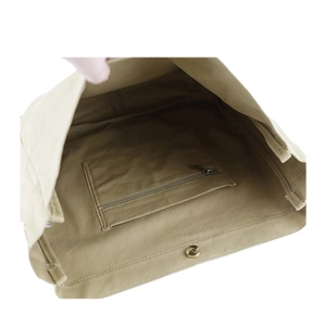 Detail view of khaki canvas tote featuring an inner zipper pocket and magnetic snap closure