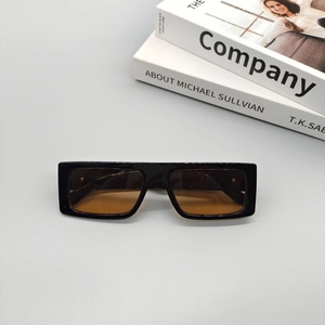 Modern square black sunglasses with brown gradient lenses on grey desk with books