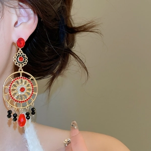 Gros plan de boucles d'oreilles bohèmes avec cristaux rouges et gouttes sur modèle