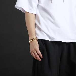 Close-up of a masculine gold double-row curb chain bracelet worn by a male model