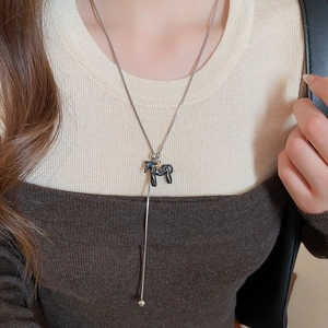 Detail of silver snake chain necklace with black pony pendant and gold star accent