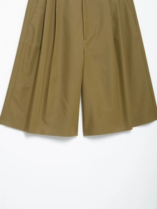 Detail view of khaki wide-leg shorts featuring front pleats and textured cotton fabric