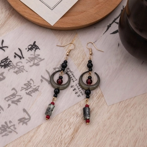 Detail of vintage moon earrings with tassel drops on a traditional Chinese scroll