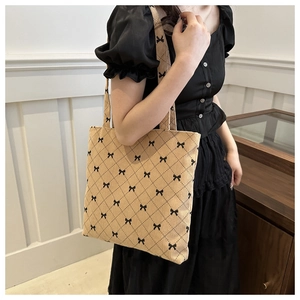 Dettaglio della borsa tote in velluto a coste beige con rombi e fiocchi neri