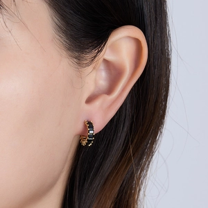 Macro side view of a model wearing a gold earring with square black zircon stones