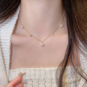 Detail shot of a gold-plated flower necklace with pearls and zircons on a model's neck