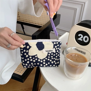 Blue polka dot canvas makeup bag with white flower pattern and purple braided handle cord