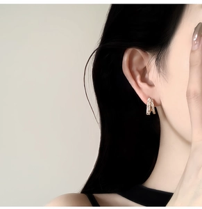 Detailed side view of 14k gold plated huggie earrings with small zircons on a model