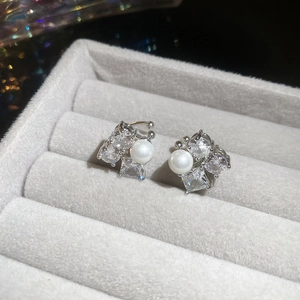 Close-up of zircon flower and pearl ear clips on grey jewelry box background
