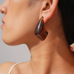 Macro shot of a woman wearing a vintage amber resin geometric stud earring with silver pin