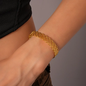 Detailed macro view of the intricate geometric hollow lace pattern on the gold metal bangle