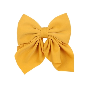 Macro shot of large mustard yellow fabric bow hair clip showing soft pleats and matte texture