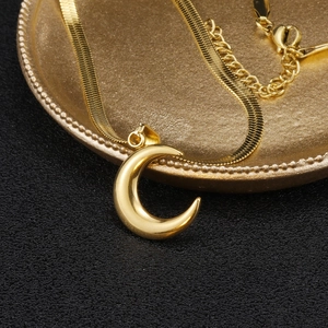 Detail of 18K gold plated herringbone chain with a crescent moon pendant on metal plate