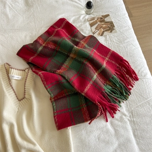 Detail shot of soft plaid scarf with fringe tassels in festive red and green colors