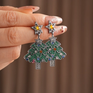 Close-up of a silver Christmas tree earring with colorful rhinestones and yellow star