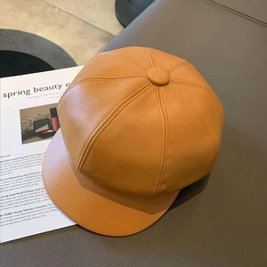 Stylish caramel faux leather newsboy cap in a minimalist vintage flat lay composition