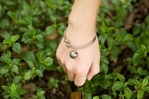 Silver stainless steel open cuff bracelet with polished bead charm on female wrist
