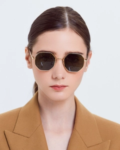 Front view of model wearing gold octagonal metal sunglasses with dark tinted lenses