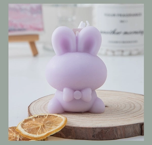 Detailed view of a lavender rabbit-shaped scented candle with bow on a wooden base
