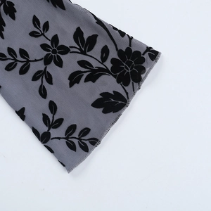 Detailed close-up of grey mesh sleeve with black floral flocking pattern textures