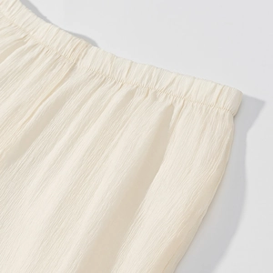 Detail of cream elastic waist on pleated lantern sleeve dress with textured fabric