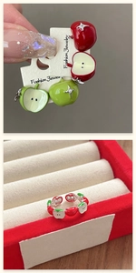 Macro detail of red and green enamel apple stud earrings with crystals in a velvet box