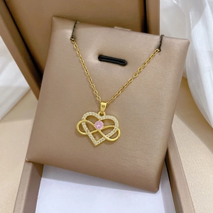 Close-up of gold heart pendant with sparkling diamonds and a pink center gemstone