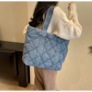 Détail du grand sac cabas matelassé en denim bleu montrant son style vintage et urbain