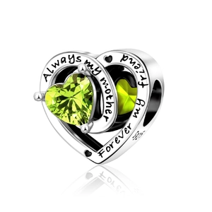 Macro detail of S925 silver heart charm with green stone and sentimental engraving