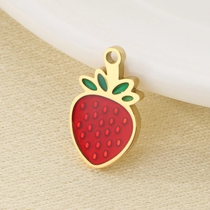 Detailed view of red and green enamel strawberry pendant on a white ceramic plate