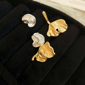 Macro view of gold and silver flower pearl earrings on a black velvet display